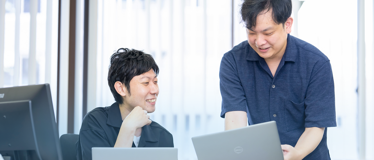 明るいオフィスで複数の社員がデスクワークを行っている様子