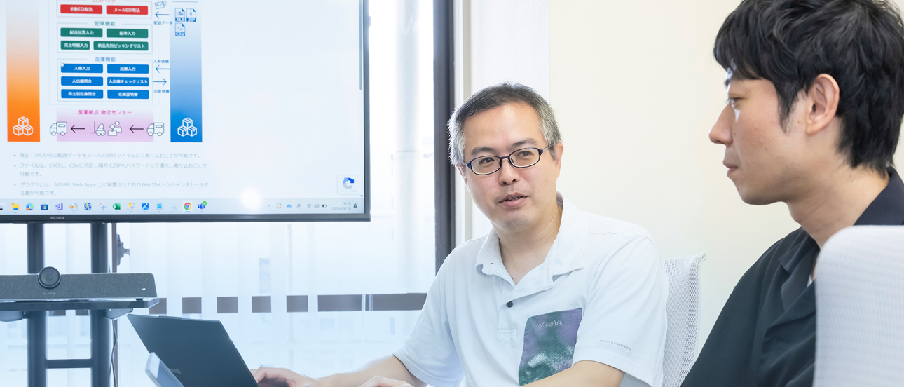 会議室で資料を見ながら意見を交わす二人の社員